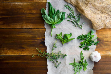 Fresh culinary herbs on wooden background: rosemary, thyme, mint, arugula, basil and parsley in...