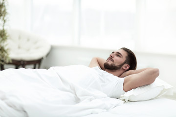 Obraz na płótnie Canvas tired man resting on a comfortable bed