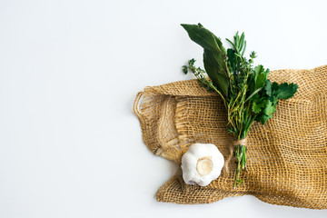 Fototapeta na wymiar Overhead image of bouquet garni with bay leaves and fresh herbs de provence on rustic towel on white background with garlic clove and text space