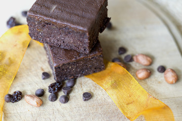 piece of chocolate brownie on plate with chocolate drops and nuts