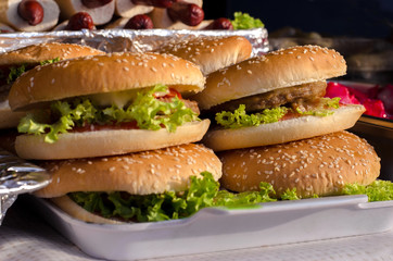 Street festival food. Ham and cheese burgers with greem salad ketchup and sauce lying on a shop window.