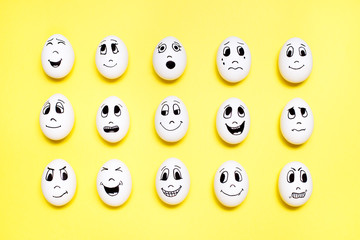 Eggs with drawn cartoon faces with various emotions in rows