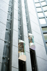 Tall modern office hall with moving glassy elevators, urban business center