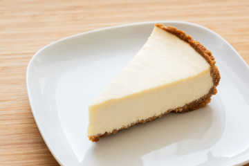 Slice of plain classical cheesecake on white plate. Selective focus