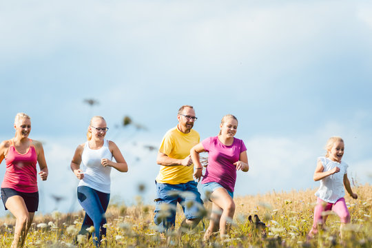 Family running for better fitness in summer jogging over a field