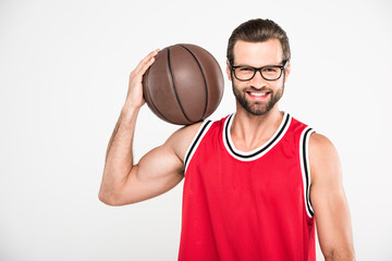 cheerful basketball player in red sportswear holding ball, isolated on white