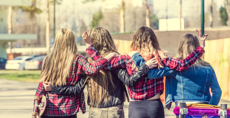 Obraz premium Back view of four girl friends hugging