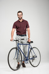 Fototapeta na wymiar elegant smiling man posing with bicycle, isolated on grey