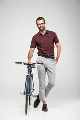 Fototapeta na wymiar smiling man posing with bicycle, isolated on grey
