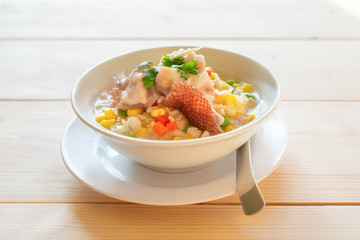 Fish and cereal porridge, side view.Fish in soft boiled cereal and rice  for breakfast on wooden table ,healthy food concept ..