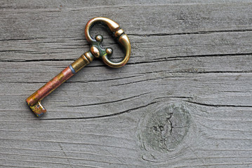 Vintage  copper key lying on a old cracked blackboard with a twig and cracks