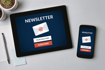 Subscribe newsletter concept on tablet and smartphone screen over gray table. All screen content is designed by me. Flat lay - obrazy, fototapety, plakaty