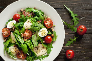 Fresh salad with tomatoes, mixed greens ,nuts, eggs, on wooden background . Healthy food.