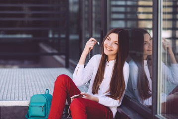 Fototapeta premium A teenage girl with a smartphone in her hands spends time outdoors