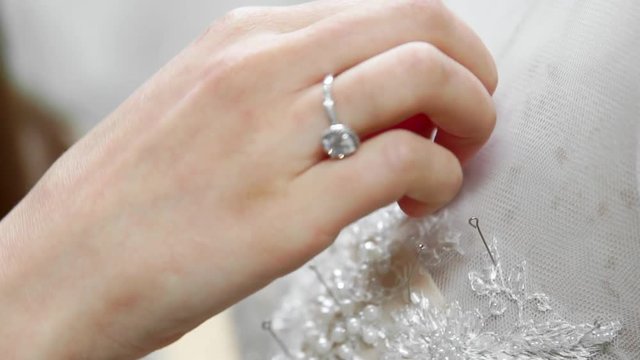 Close-up fashion designer for brides in his Studio pins needles lace wedding dress. Seamstress creates an exclusive wedding dress. Secure with pins and needles outline. Small private business