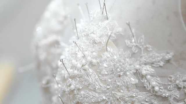 Close-up fashion designer for brides in his Studio pins needles lace wedding dress. Seamstress creates an exclusive wedding dress. Secure with pins and needles outline. Small private business