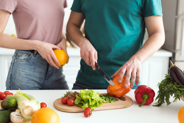 Obraz na płótnie Canvas cropped image of boyfriend cutting vegetables for vegetarian salad at kitchen
