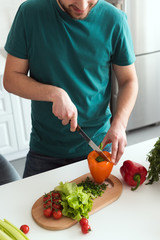 cropped image of man cutting vegetables for vegetarian salad at kitchen