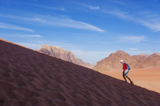Man runs up the dune in the Wadi Rum desert, Jordan