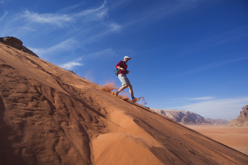 Man runs down the dune in the Wadi Rum desert, Jordan