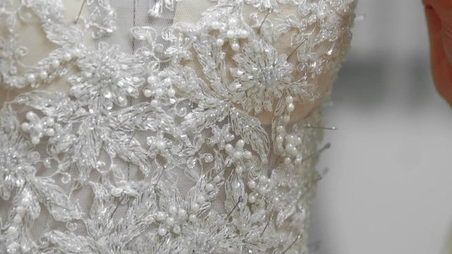 Close-up fashion designer for brides in his Studio pins needles lace wedding dress. Seamstress creates an exclusive wedding dress. Secure with pins and needles outline. Small private business