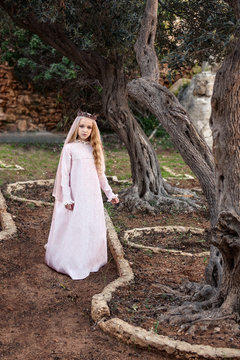 a little princess of spirits and fairies stands in the enchanted mysterious magic forest in a wedding dress with a veil and crown