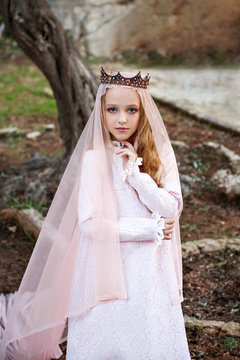 dolly princess of the fairy elves stands in a magical enchanted forest and enchantingly looks