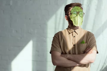 Poster obscured view of man with savoy cabbage leaf and eyeglasses on face, vegan lifestyle concept © LIGHTFIELD STUDIOS