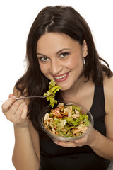 young beautiful woman eating a caaesar salad to go on white background