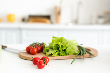 cherry tomatoes and salad leaves on cutting board in kitchen