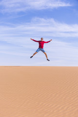 Tourist jumps on dune of Wadi Araba desert, Jordan