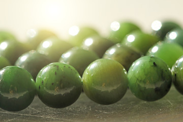 Natural green jade nephrite mineral stones beads. Green and grassy natural background made of round stone beads © Ekaterina