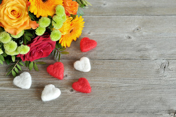 Blumenstrauß und Filzherzen auf Holz
