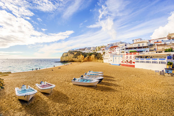 Fototapeta na wymiar Sandy beach with colorful boats and cliffs and white architecture in Carvoeiro, Algarve, Portugal