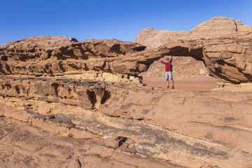Fototapeta na wymiar Tourist on rock. Wadi Ram desert. Stone bridge. Jordan landscape