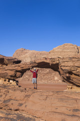 Tourist on rock. Wadi Ram desert. Stone bridge. Jordan landscape