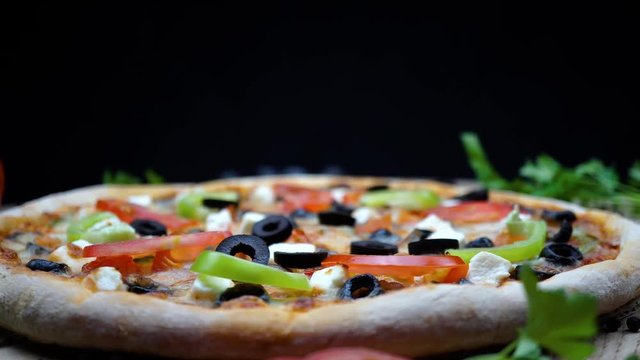 Macro shot of delicious vegetable pizza rotating on the wooden table in the studio. 4K