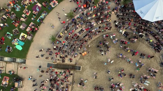 Top view of people sitting on a late summer evening open air event at the Donau shore in Ingolstadt, Germany (next to Klenzepark). Camera on rotation and lift up.