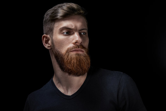 Close up image of serious brutal bearded man on dark background Confident and dramatic concept