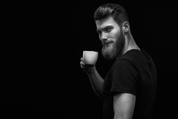 Black and white side view dramatic light shot of happy smiling young bearded man holding white...