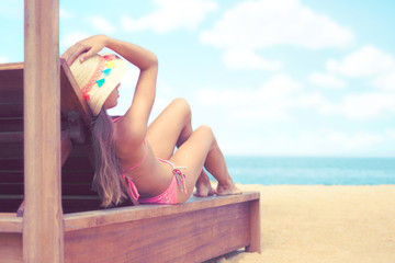 Young woman whit sun hat lying on sun bad enjoys sunbath at the beach with the sea and sky in the...