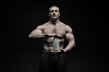 Fototapeta na wymiar Bodycare and hygiene for sportsman. Bodybuilder hold shampoo or gel bottle. Man athlete with fit torso and ab. Spa bath or shower cosmetic after training in gym, vintage