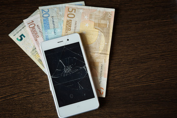 smartphone with broken screen on a background of Euro bills. Saving