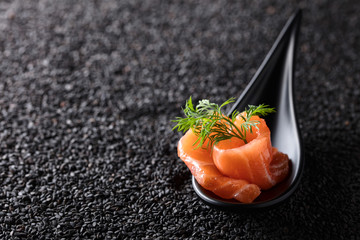 Salted salmon with dill on the background of black sesame.