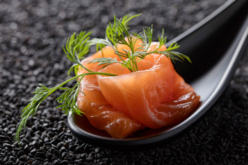 Salted salmon with dill on the background of black sesame.