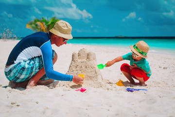 father and son building castle on sand beach