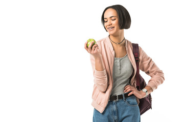 smiling female african american student with backpack holding apple, isolated on white