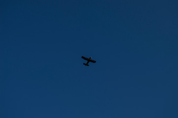 The small flying airplane on a blue background. Clear sky