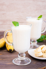 Banana smoothie with mint leaves in glasses on a wooden table