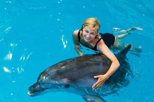 Coach swims in the water with dolphins. Dolphin Assisted Therapy.
